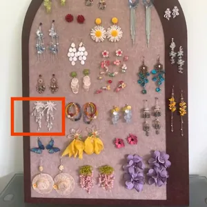 Detailed view of white beaded tassel earrings on a plush jewelry display board