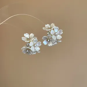 Close-up of elegant floral rhinestone stud earrings featuring pearlescent white petals