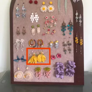 Detail shot of yellow fabric flower petal tassel earrings displayed on a felt jewelry board.
