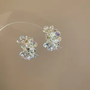 Close-up detail of iridescent floral stud earrings with sparkling central crystals