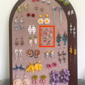 Detailed view of forest style floral tassel dangle earrings on a beige display board