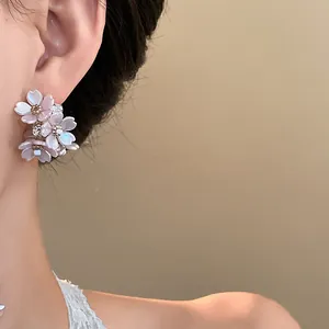 Close-up of elegant pink floral earrings with sparkling diamond accents on model's ear