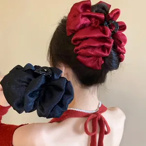 Macro view showing the elegant pleated fabric texture of large red and black hair claw clips