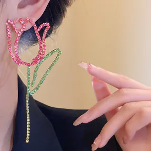 Close-up view of sparkling pink and green rhinestone tulip earrings on model's ear