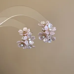 Macro view of French style pink resin flower stud earrings with sparkling rhinestone centers
