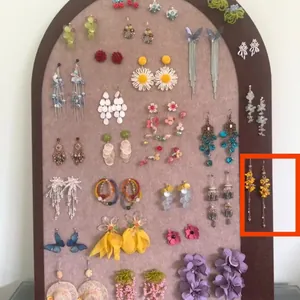 Close-up detailed view of yellow floral tassel earrings on a jewelry display board
