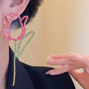 Detail view of oversized tulip flower earrings with pink and green rhinestones on model.