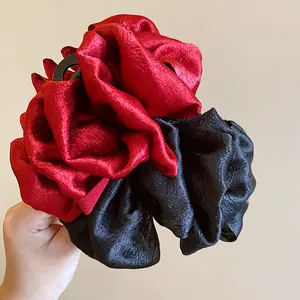 Close-up of a multi-layered pleated fabric hair claw clip in vibrant red and black colors
