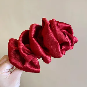 Detailed view of a red pleated fabric hair claw clip with a multi-layered bow design
