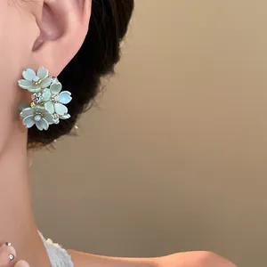 Macro view of French style floral earrings with iridescent petals and crystal center