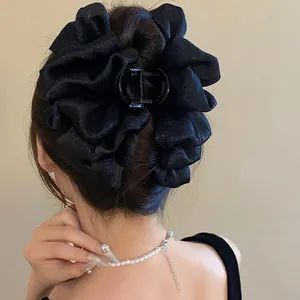 Elegant back view of black pleated fabric flower hair claw clip styling a large bun.