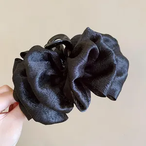 Detailed view of a black layered fabric scrunchie hair claw clip with pleated texture