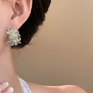 Elegant detail of French-style crystal floral stud earrings worn by an Asian model