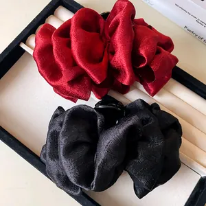 Close-up detail of red and black pleated fabric bow hair claw clips in display box
