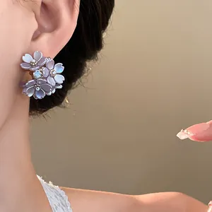 Detailed close-up view of elegant purple flower stud earrings with a sparkling diamond center
