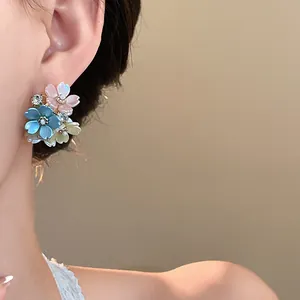 Close-up detail of elegant floral stud earrings with rhinestones on a female ear model