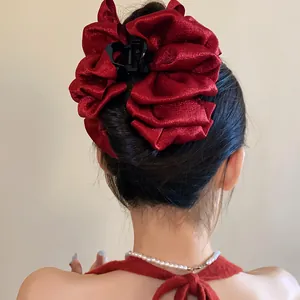 Detailed view of a large red ruffled fabric hair claw clip used for a stylish hair bun.