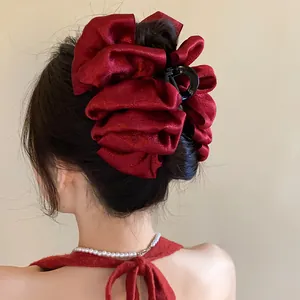 Detailed view of a large dark red pleated fabric hair claw clip styled in a sleek bun