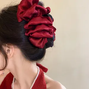 Close-up of a large red pleated fabric hair claw clip on an elegant updo hairstyle.