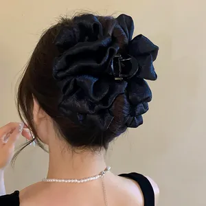 Macro view of a black pleated fabric hair claw clip showing texture on an elegant bun