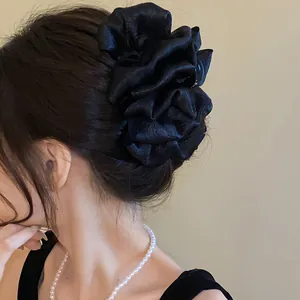 Close-up of an elegant black ruffled fabric hair claw clip styled in a sophisticated updo