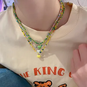 Handmade layered colorful seed bead necklace featuring three heart pendants on a model.
