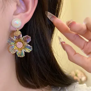 Close-up view of elegant vintage iridescent resin flower drop earrings worn by a model