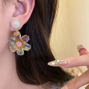 Close-up of vintage resin flower drop earrings with iridescent petals and pink crystal