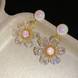 Detailed macro view of iridescent resin flower earrings featuring a gold LOVE disc and pink crystal