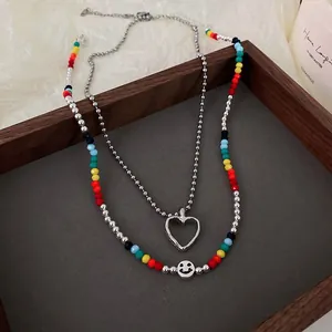 Detail view of double-layer necklace with colorful beads, heart pendant and smiley face.