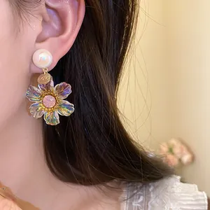 Close-up of iridescent resin flower drop earring with pink rhinestone and LOVE charm details.