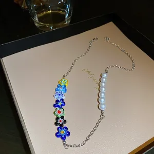 Close-up detail of a vibrant colorful flower and pearl beaded necklace on a display tray