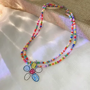 Macro view of colorful beaded necklace featuring a hand-drawn style flower pendant