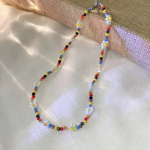 Detail view of colorful beaded necklace with delicate white daisy flower accents