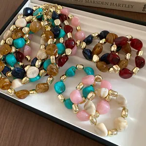 Close-up of vintage irregular stained bead necklaces with gold-tone accents in a display tray