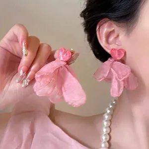 Vista dettagliata di orecchini a cuore in organza rosa indossati da una modella