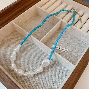 Close-up of a turquoise beaded necklace with irregular white pearls in a wooden box