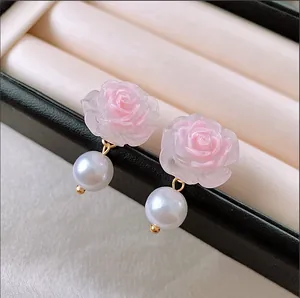 Close-up detail of sweet pink resin rose earrings with elegant white pearl drops