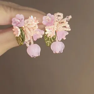 Close-up of delicate pink flower earrings featuring intricate seed beads and glass petals