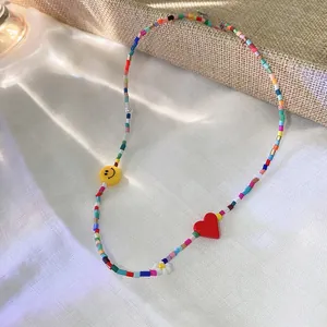 Close-up detail of a colorful beaded necklace featuring a red heart and smiley face bead