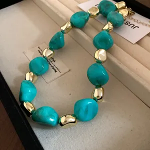 Close-up of irregular turquoise and gold beaded necklace in a jewelry display box