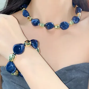 Detail view of a retro blue marbled bead necklace and bracelet set on a model