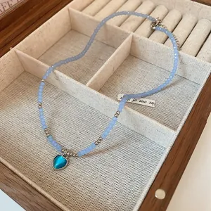 Detail view of light blue beaded necklace with a charming blue heart pendant in box.