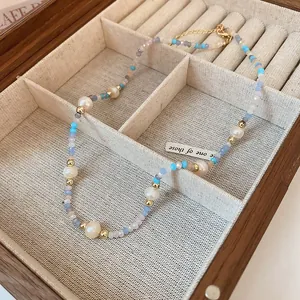 Close-up of a dainty necklace with colorful beads and white pearls in a wooden jewelry box