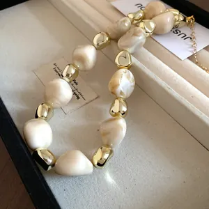 Close-up detail showing the irregular dyed beads and gold accents of a retro fashion necklace