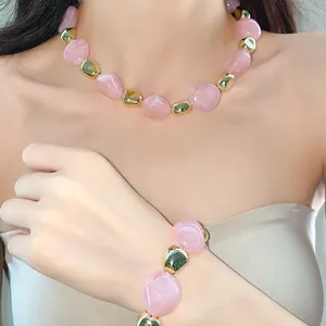 Detail showing irregular pink marble beads and gold jewelry set worn by a model