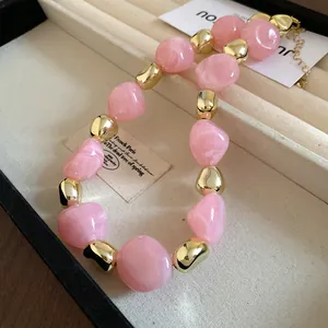 Detailed close-up showing pink marbled beads and golden metallic accents of this vintage necklace