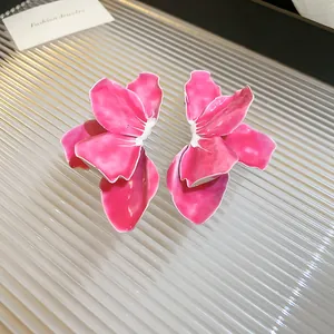 Close-up of elegant pink enamel flower stud earrings with intricate petal details.