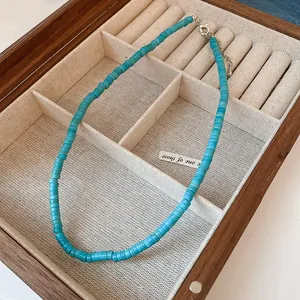 Detailed macro view of vibrant turquoise blue beaded necklace in a wooden jewelry tray