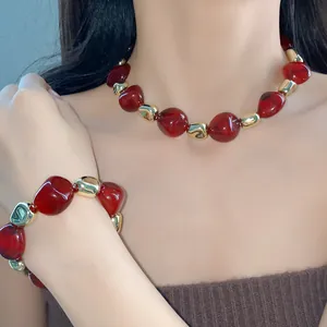Detailed view of marbled red and gold irregular beaded necklace and bracelet on model